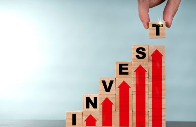 Invest spelled out letter by letter on top of red arrows facing up