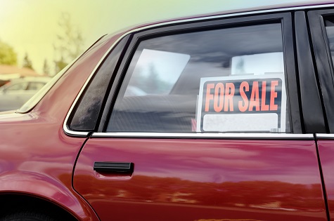 Shiny red car with a for sale sign